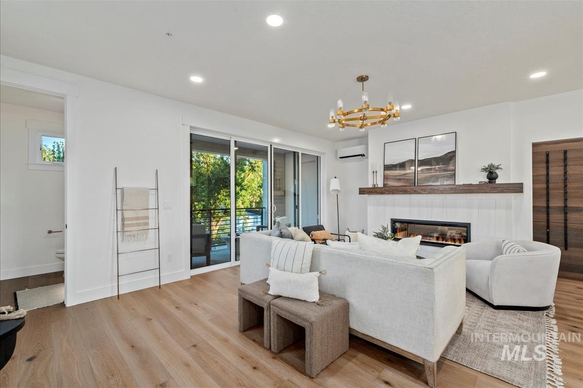 3255 West Moore Street Boise, ID 83702 - Photo 7 of 44 Living area featuring light wood finished floors, a tiled fireplace, recessed lighting, a chandelier, and a wall unit AC