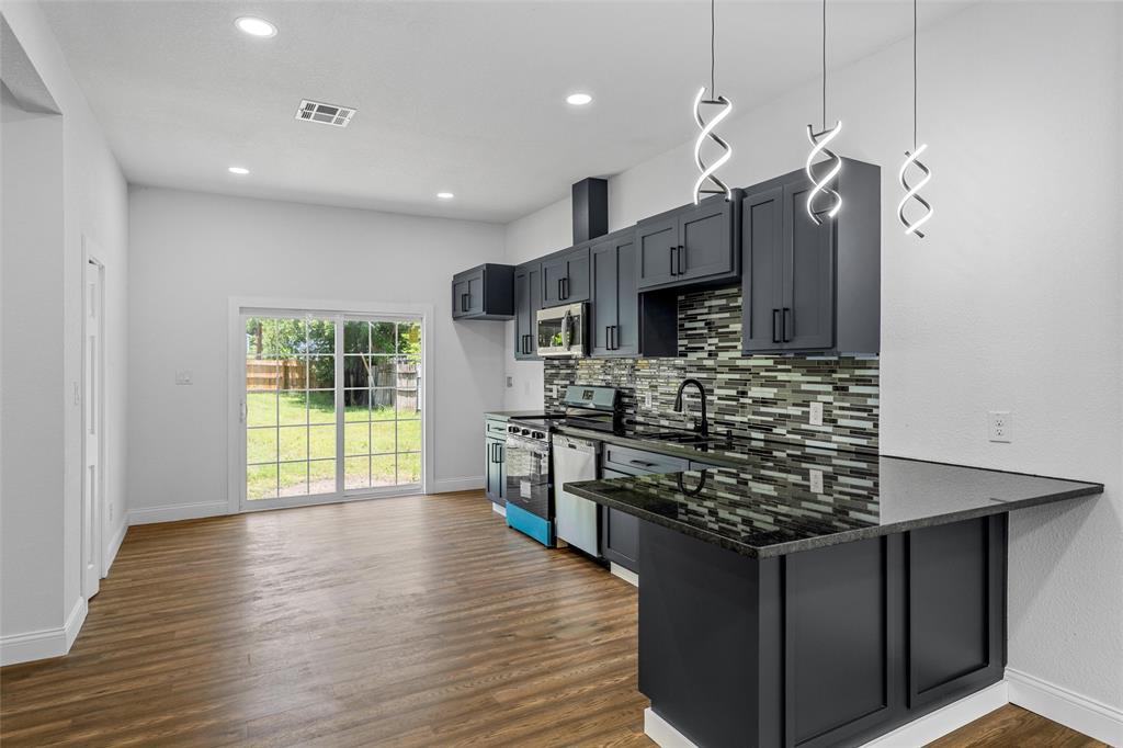 2023 Bosque Boulevard Waco, TX 76707 - Photo 8 of 26 Modern kitchen featuring dark cabinetry, dark countertops, and a full tile backsplash