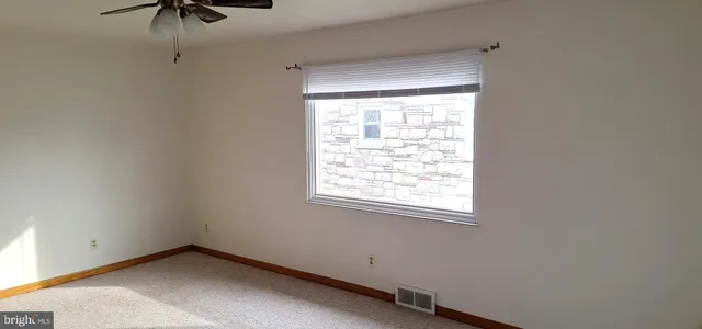 an empty room with a window and a ceiling fan