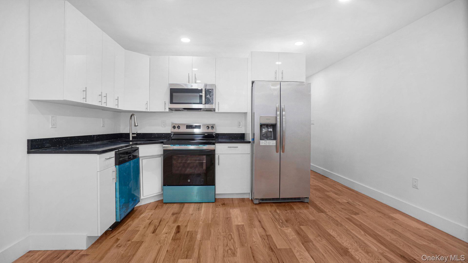 3968 Duryea Avenue Bronx, NY 10466 - Photo 11 of 30 Kitchen with stainless steel appliances, white cabinetry, light wood-style flooring, recessed lighting, and dark stone counters