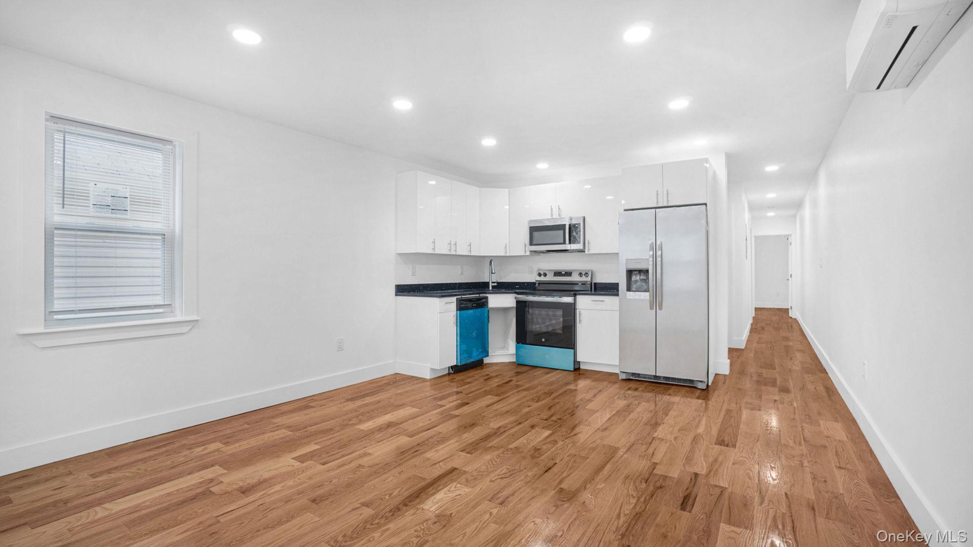 3968 Duryea Avenue Bronx, NY 10466 - Photo 13 of 30 Kitchen featuring white cabinetry, stainless steel appliances, dark countertops, light wood-style flooring, and a wall mounted air conditioner