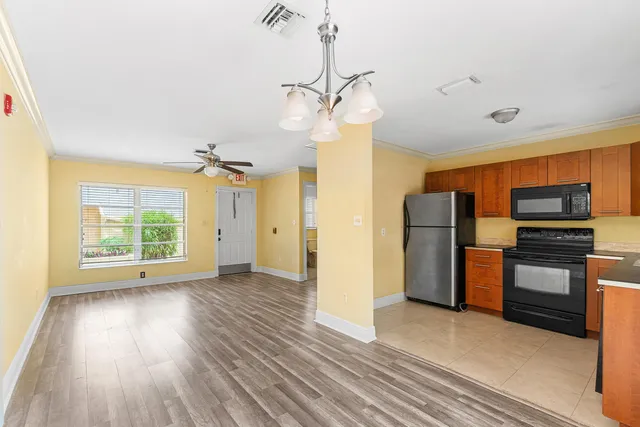 a view of a kitchen with a ceiling fan a refrigerator and wooden floor