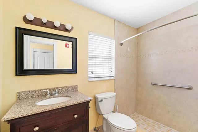 a bathroom with a granite countertop toilet sink and mirror