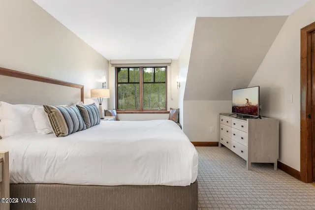 a large bed sitting in a bedroom next to a window