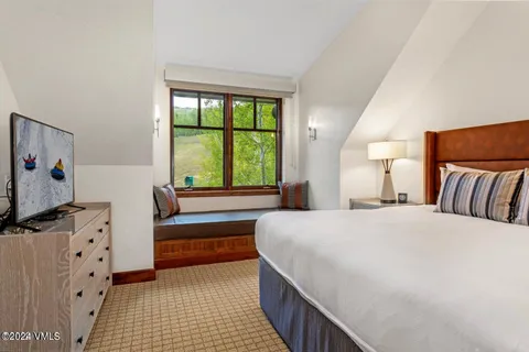 a bedroom with a bed and a flat tv screen on dresser