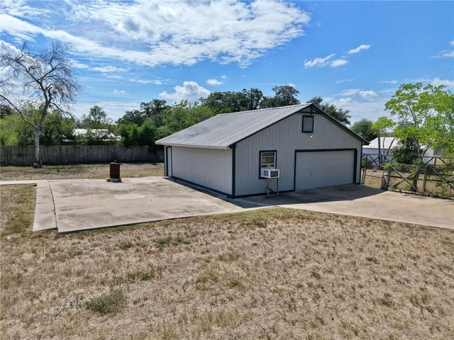 a view of a backyard with large trees and wooden fence