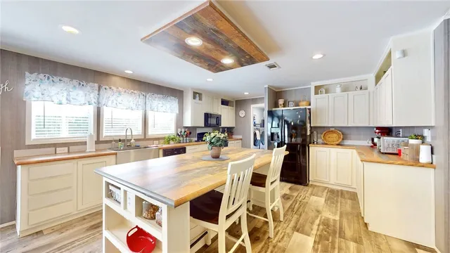 a view of a kitchen with kitchen island a large counter top space a sink stainless steel appliances and cabinets
