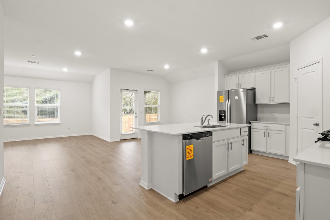 2408 Bronc Buster Way Leander, TX 78641 - Photo 23 of 24 a large kitchen with stainless steel appliances granite countertop a large counter top and wooden floors