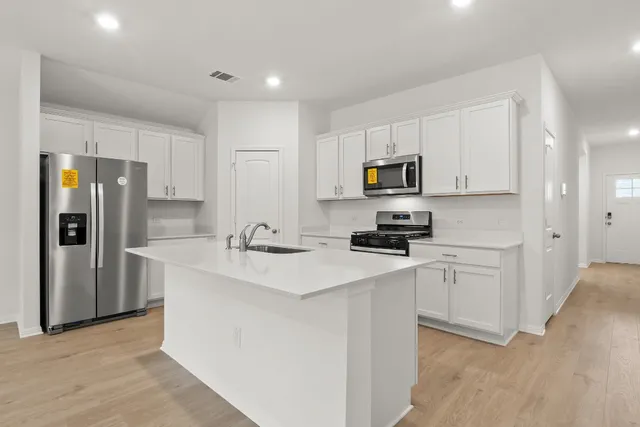 a large kitchen with stainless steel appliances granite countertop a large counter top and wooden floors