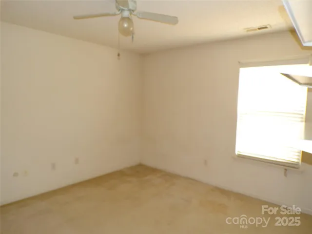 an empty room with a window and a fan