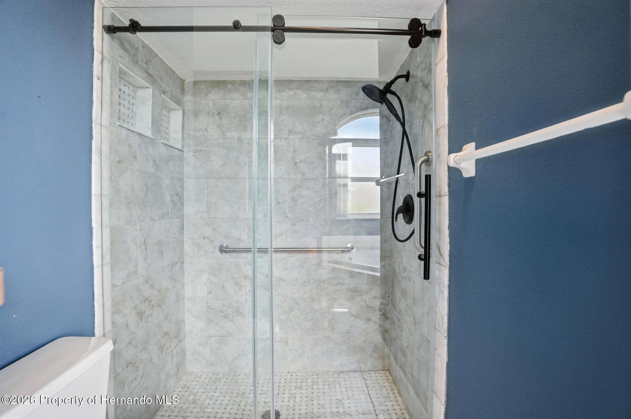 18131 Rivard Boulevard Brooksville, FL 34604 - Photo 29 of 66 a bathroom with a glass shower door and mirror