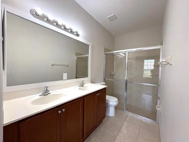 a bathroom with a double vanity sink mirror and toilet