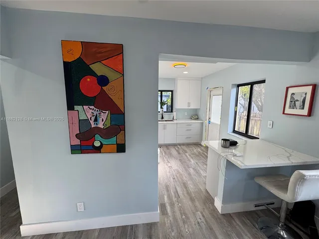 a living room with painting on the wall and a wooden floor