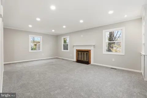 an empty room with windows and fireplace