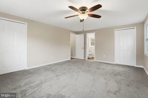 an empty room with chandelier fan and windows
