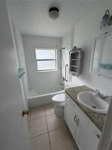 a bathroom with a granite countertop sink toilet a mirror and tub