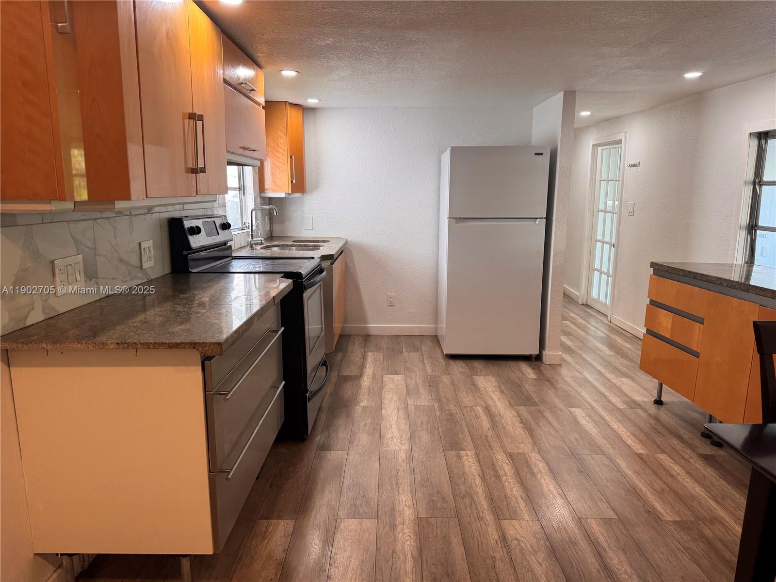 a kitchen with a sink a refrigerator a microwave and cabinets