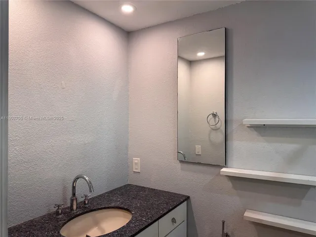 a bathroom with a granite countertop sink a toilet and mirror