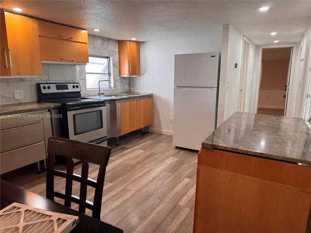 a kitchen with granite countertop a refrigerator and a stove top oven