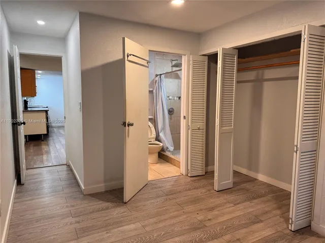 a view of a hallway with wooden floor and a bathroom