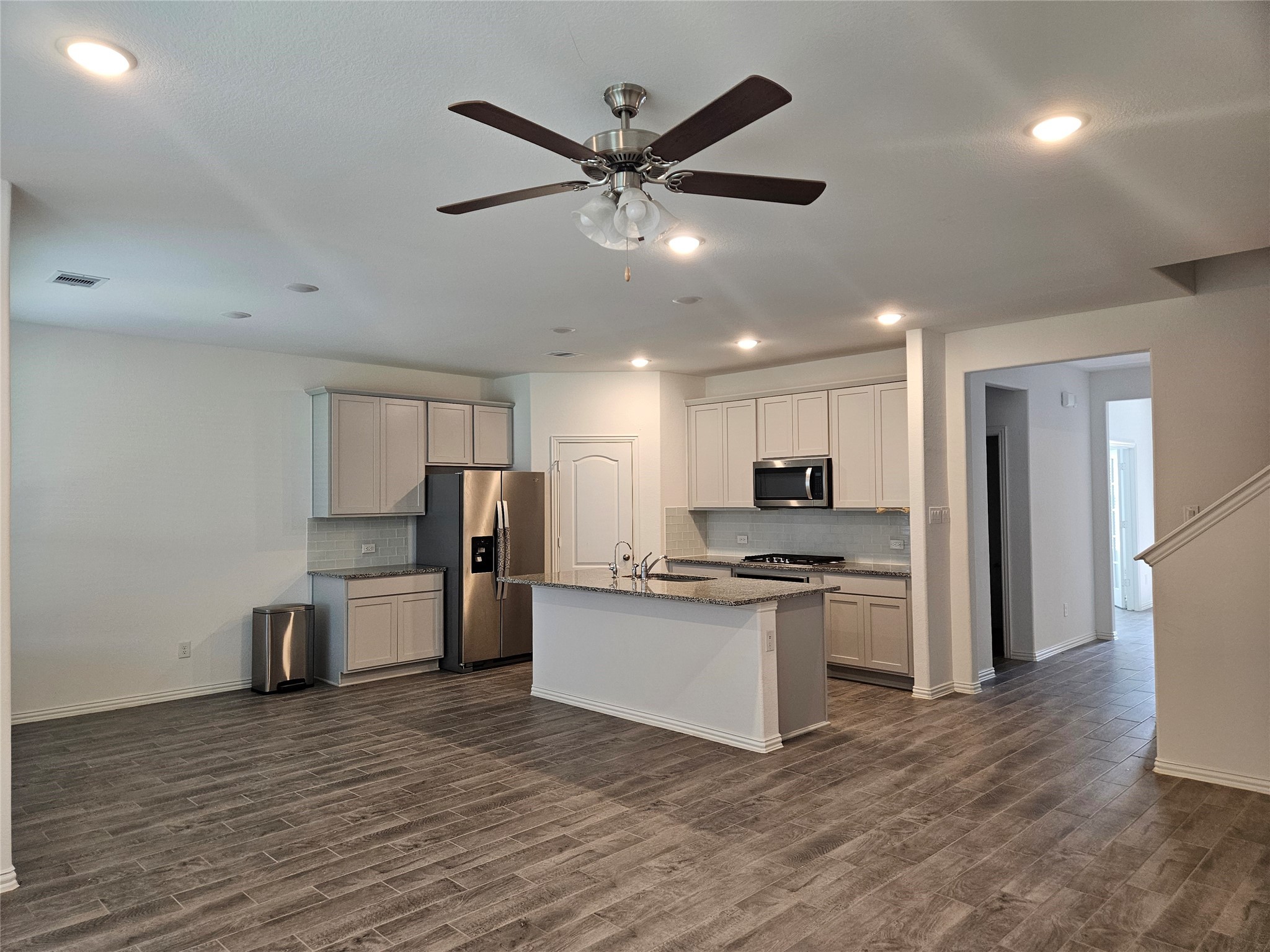 7927 Chukka Drive Fulshear, TX 77441 - Photo 3 of 12 a kitchen with stainless steel appliances a refrigerator a sink dishwasher a stove and a microwave oven with wooden floor