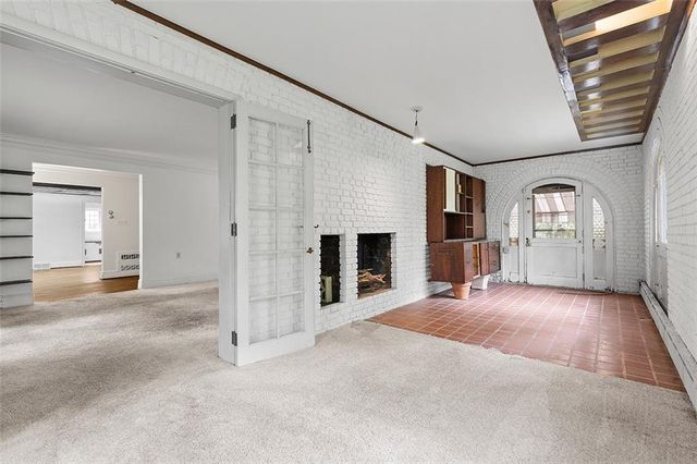 an empty room with windows and fireplace