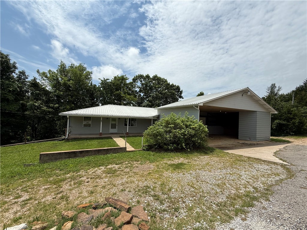 4250 AR 7 Jasper, AR 72641 - Photo 35 of 47 Ranch-style exterior with a metal roof, featuring a covered porch, light gray siding, a prominent covered carport, and surrounding mature trees