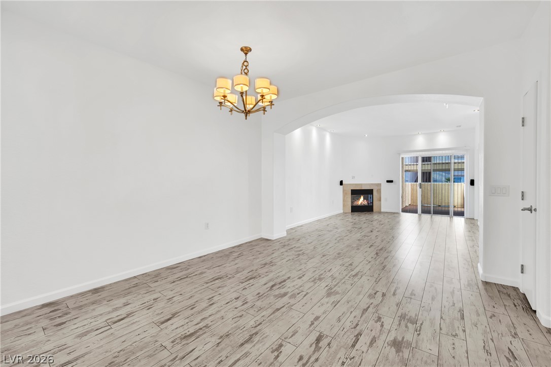 8725 West Flamingo Road, Unit 110 Las Vegas, NV 89147 - Photo 23 of 30 A graceful chandelier illuminates the pristine hardwood floors, leading to a modern fireplace and glass sliding doors.