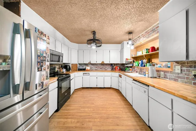 a large kitchen with stainless steel appliances lots of counter space a sink and cabinets