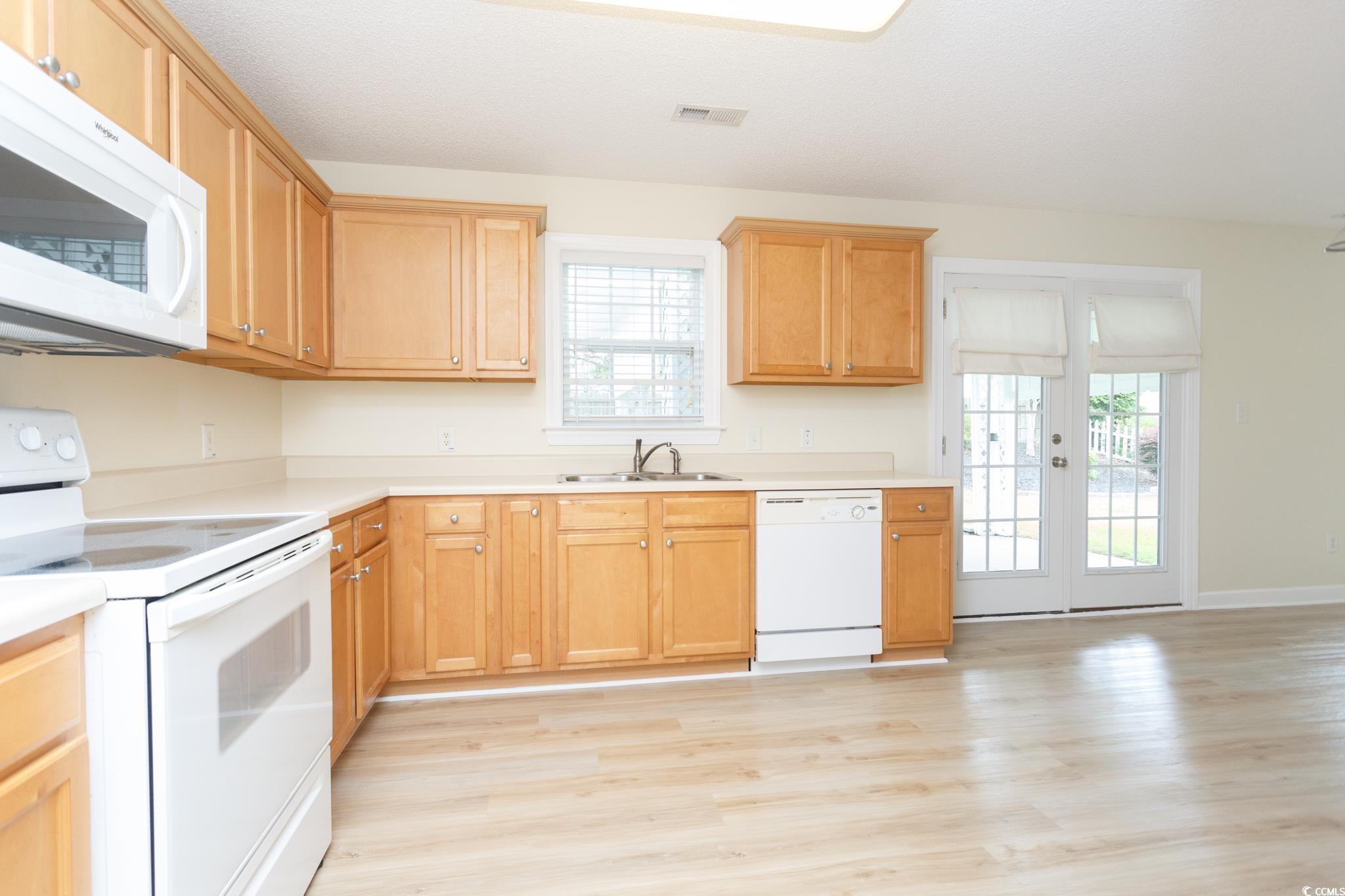 112 Molinia Drive Murrells Inlet, SC 29576 - Photo 12 of 40 Kitchen with white appliances, a sink, light wood-style flooring, light countertops, and baseboards