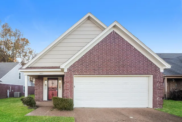 a view of house with yard and parking