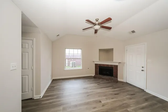 a view of an empty room with a window and fireplace