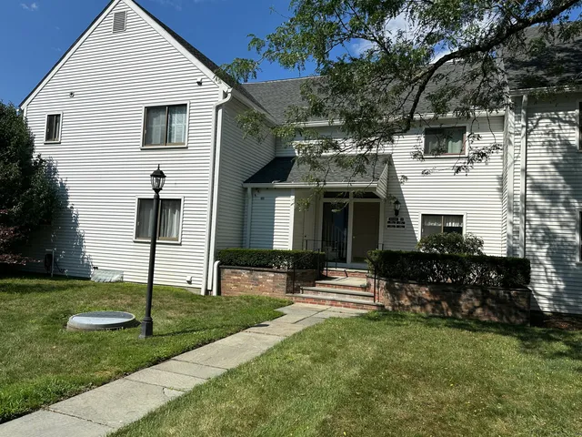 a view of a white house with a big yard and large tree