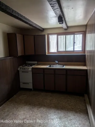 a kitchen with a sink a stove cabinets and a window