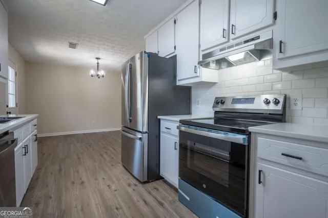 a kitchen with stainless steel appliances wooden floor sink and wooden cabinets