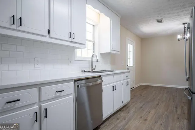 a kitchen with granite countertop white cabinets white appliances and a wide window