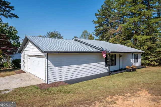 a view of a house with a yard and large tree
