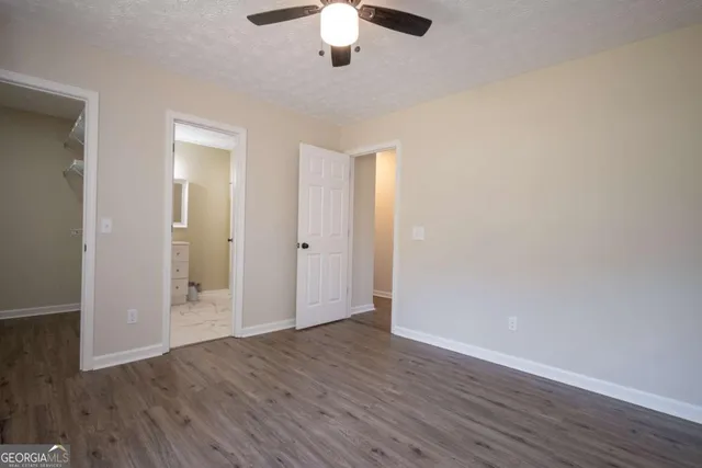 an empty room with wooden floor chandelier fan and closet area