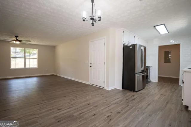an empty room with wooden floor a ceiling fan and windows