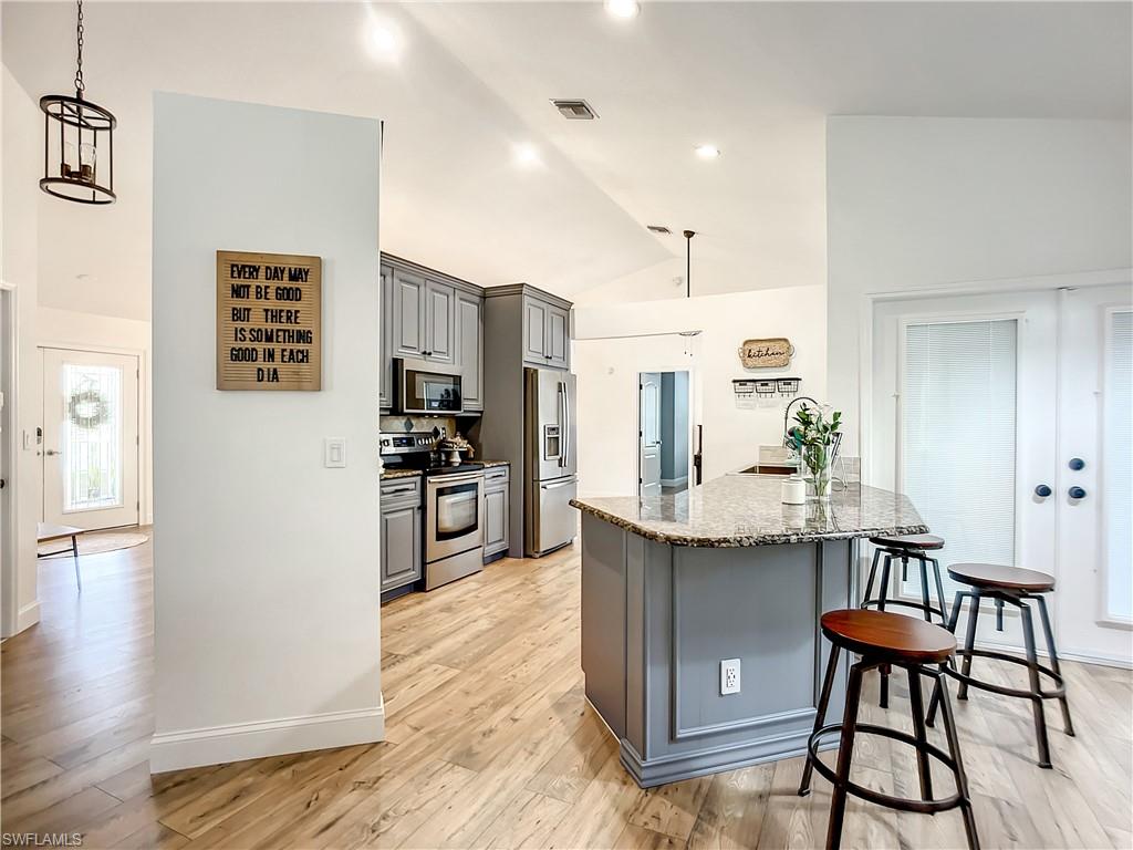 10231 Boca Circle Naples, FL 34109 - Photo 12 of 44 a kitchen with stainless steel appliances kitchen island granite countertop a refrigerator and a stove top oven