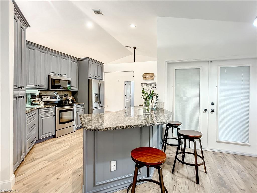 10231 Boca Circle Naples, FL 34109 - Photo 13 of 44 a kitchen with stainless steel appliances kitchen island granite countertop a kitchen island hardwood floor and a sink