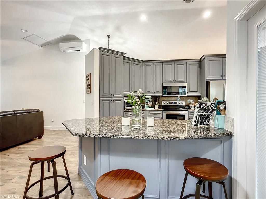 10231 Boca Circle Naples, FL 34109 - Photo 14 of 44 a kitchen with stainless steel appliances granite countertop a table chairs stove and refrigerator
