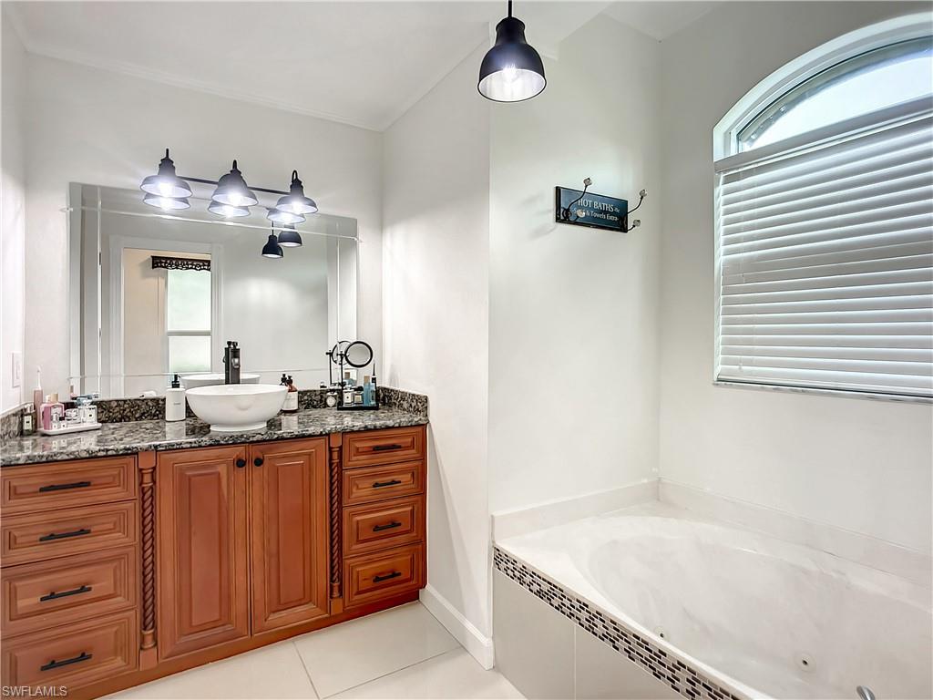 10231 Boca Circle Naples, FL 34109 - Photo 24 of 44 a spacious bathroom with a granite countertop sink a mirror and a bathtub
