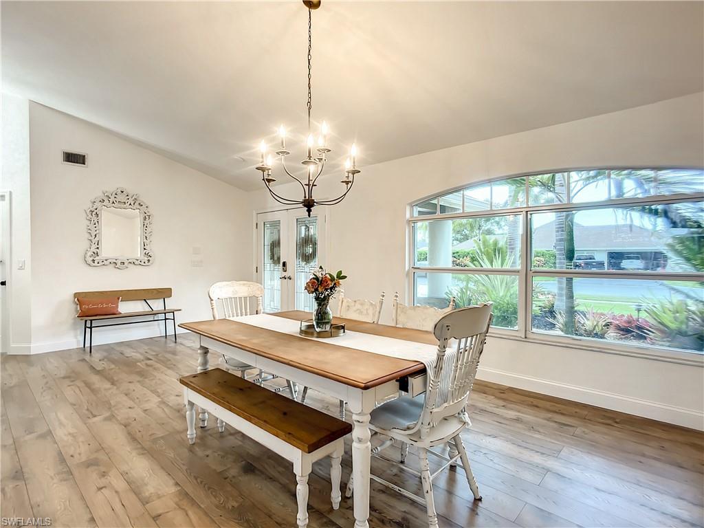 10231 Boca Circle Naples, FL 34109 - Photo 9 of 44 a dining room with wooden floor a chandelier a wooden table and chairs