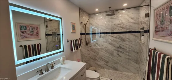 a bathroom with a sink a toilet a mirror and shower