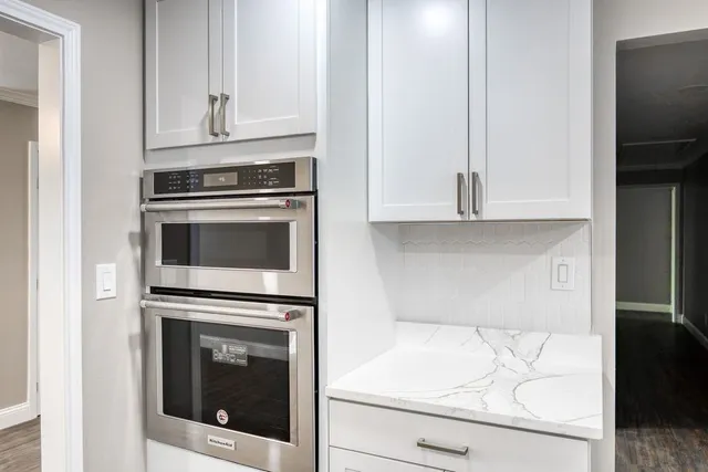 a kitchen with granite countertop white cabinets and stainless steel appliances