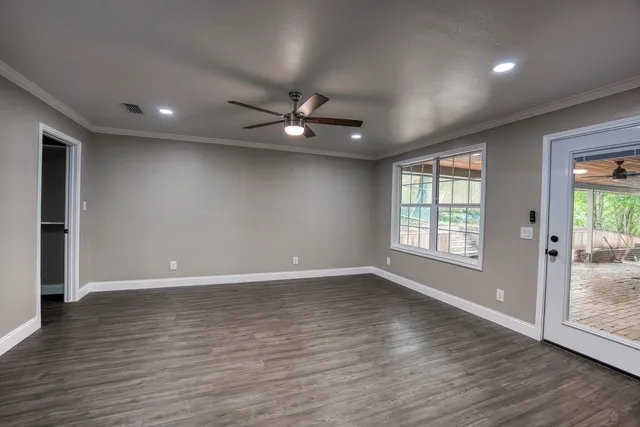 a view of an empty room with wooden floor and a window