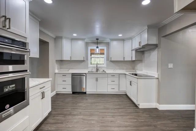 a kitchen with granite countertop a sink cabinets stainless steel appliances and wooden floor