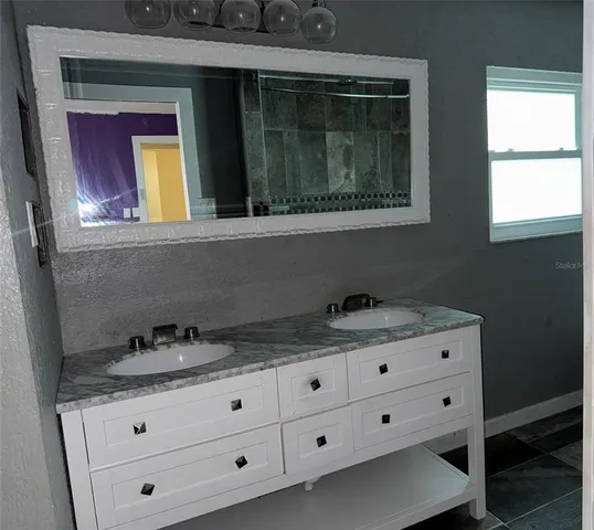a bathroom with a granite countertop sink and mirror