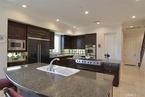 a kitchen with kitchen island granite countertop a refrigerator and a sink